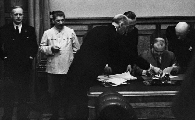 Молотов подписывает, а Сталин стоит в стороне
